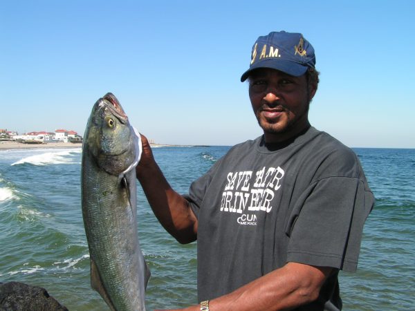 man holding a bluefish he caught fishing